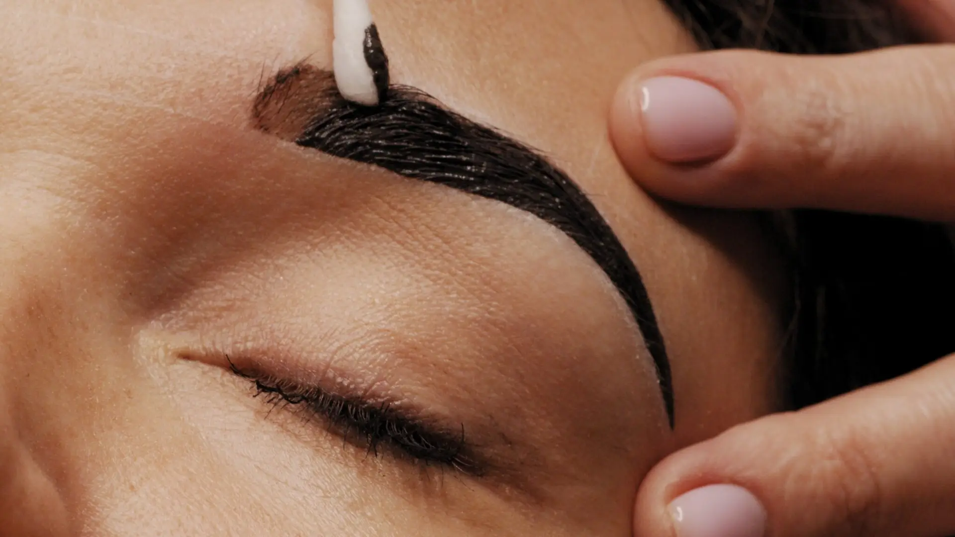 Cosmetologist removes black eyebrow paint after coloring. Beauty treatment procedures