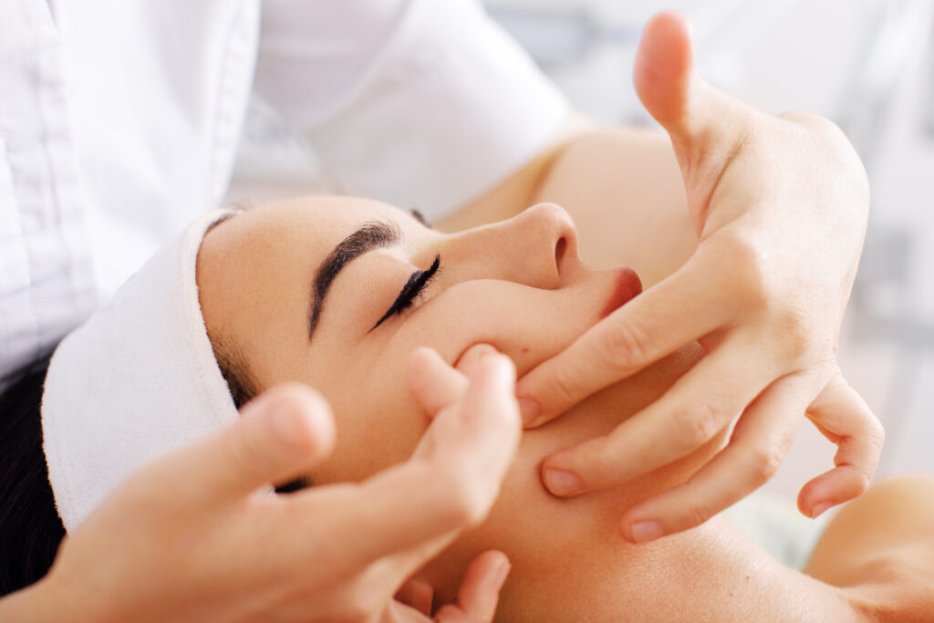 Beautiful woman having spa facial massage in beauty salon